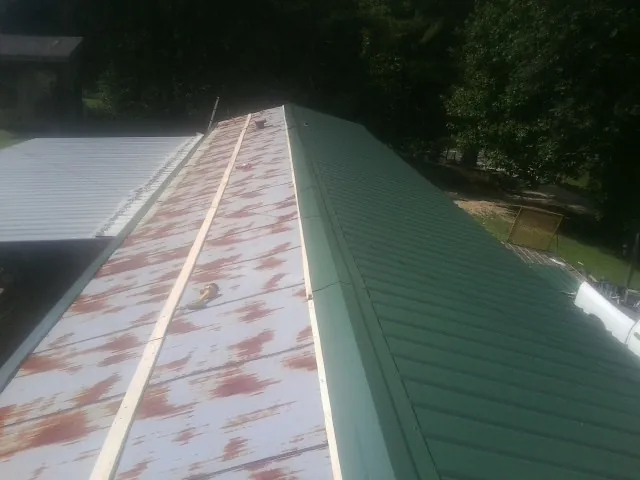 Old rusted panels beside newly installed green metal roofing — Wind Damage Roof Repair by Roofing Brothers in Vernon Rockville