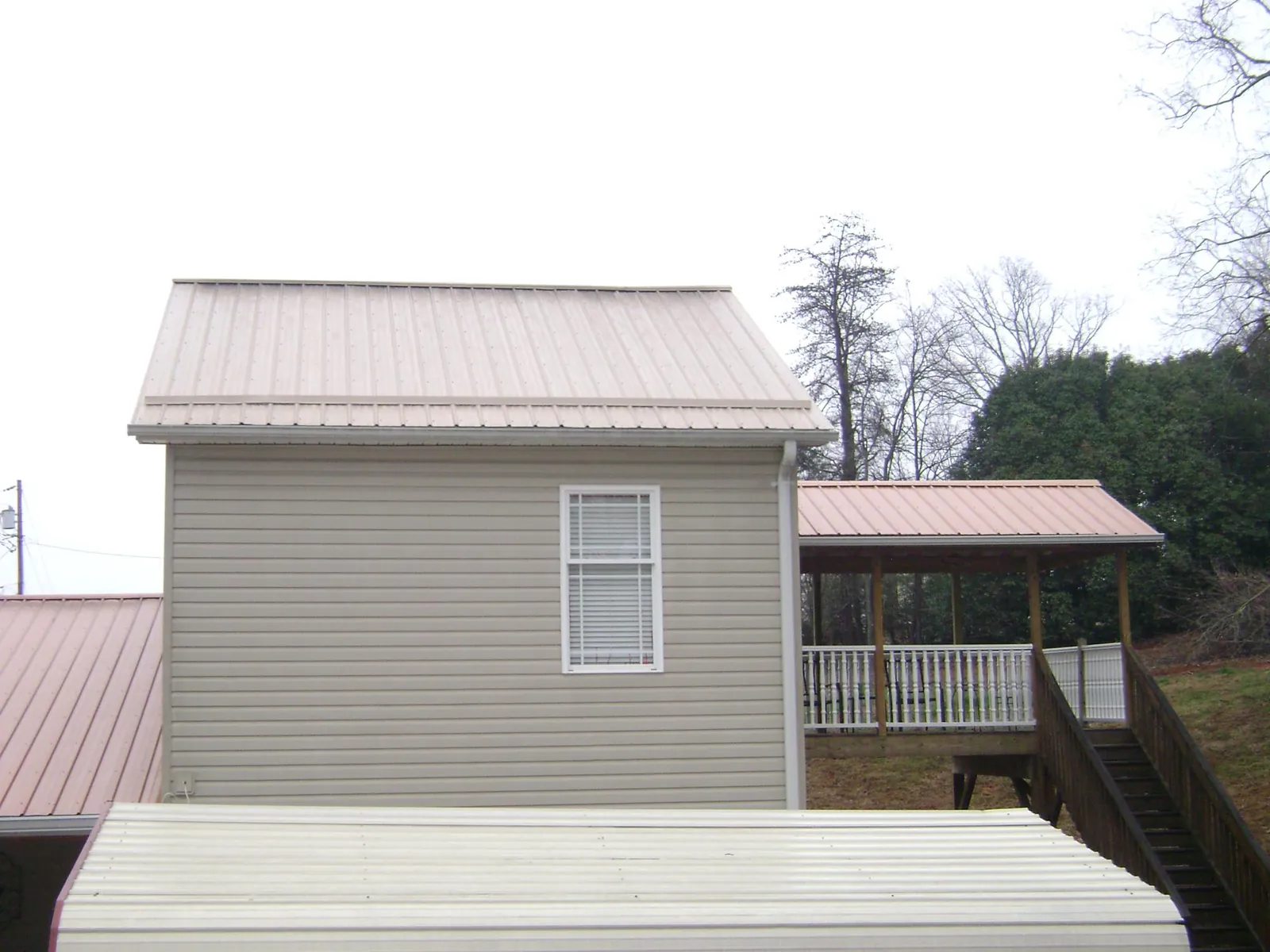 Tan metal roofs on a two story addition and attached porch, from a Roof Replacement job in Vernon Rockville